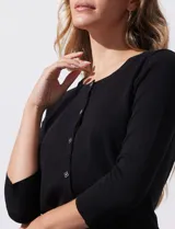 Cardigan blanco de tejido fino con abertura central y botones.