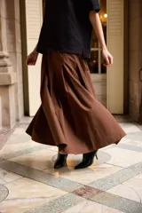 Falda larga de corte acampanado con tablas anchas, confeccionada en algodón color marrón.