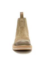 Bota tipo Chelsea de Caterpillar, confeccionada en gamuza color tostado con paneles elásticos laterales en color verde oliva. Presenta suela de goma dentada y tiradores en la parte superior trasera.