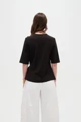 Remera negra de manga corta, con cuello redondo y diseño holgado con detalle de lazo para anudar en la cintura.