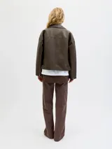 Campera estilo biker de efecto cuero en color marrón desgastado, con cuello solapa, cierre frontal asimétrico, bolsillos laterales con cierre y bolsillo pequeño con solapa y botón a presión. Presenta un corte holgado y diseño versátil.