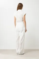 Mono largo blanco con broderie, corte palazzo, cuello camisero, mangas cortas y cinturón de lazo.