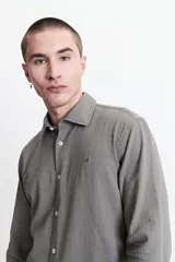 Camisa de manga larga lisa color gris con textura y logo bordado en el pecho. Corte clásico con cuello abotonado y cierre frontal con botones.