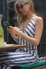 Top con cuello halter, a rayas verticales blancas y grises, con cierre frontal de botones.