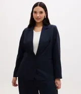 Blazer de corte sastre confeccionado en crepé, con diseño alargado y cierre frontal de doble abotonado con botones forrados. Presenta solapas clásicas y estructura recta.