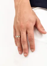 Anillo liso de acero quirúrgico hipoalergénico, color dorado con banda central plateada.