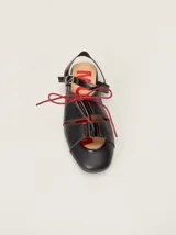 Sandalias planas tipo slingback de cuero marrón, con diseño delantero calado, cierre de cordones y tira trasera ajustable con hebilla.