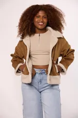 Campera tipo gamulán de gamuza color marrón con interior y solapas de corderito sintético color beige. Presenta cierre frontal con botones, mangas largas y corte holgado.