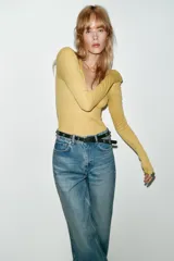 Jeans de tiro alto color azul claro, con cinco bolsillos y pernera recta que se estrecha hacia el tobillo. Incluye un cinturón negro con detalles metálicos. Cierre frontal con cremallera y botón.