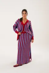 Pollera larga tejida a rayas verticales rojas y celestes, con pretina elástica y tajos laterales.