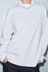 Camiseta blanca de algodón con cuello alto, manga larga y bajo recto, de corte regular.