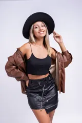 Minifalda negra de cuero sintético con cremalleras diagonales y cinturón con hebilla metálica.