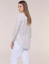 Camisa de calce relajado color celeste, confeccionada en tejido de textura suave y fluida. Presenta cuello camisero y abotonadura frontal, mangas largas con puño ancho y ruedo curvo.