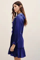 Vestido corto azul de viscosa con cuello en V, volados en el escote, mangas largas con puños fruncidos y falda con volado en el ruedo. Incluye un lazo para ajustar en la cintura.