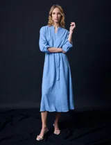 Vestido maxi color beige, con cuello mao y escote en V. Presenta mangas largas con presilla y botón para regular el largo, y un lazo ajustable en la cintura que marca la silueta.