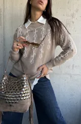 Sweater de punto color beige con bordado de flores blancas en el frente y las mangas, cuello redondo y puños acanalados.