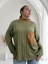 Polera verde oliva de tejido trenzado con cuello alto y bolsillo de cuero color marrón.