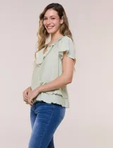 Blusa de satén texturizado color verde menta, con escote en V y volados que bordean el cuello. Presenta mangas cortas acampanadas y doble nivel de volados en la parte inferior, formando una silueta péplum.