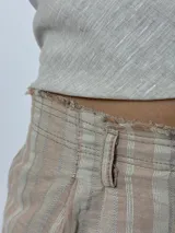 Pantalón largo de lino a rayas verticales en tonos beige, rosa y gris, con cintura alta y corte recto.