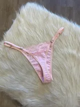 Tanga rosada de algodón con encaje en la parte delantera y tiras regulables.