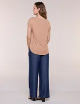 Remera blanca de punto acanalado con escote redondo adornado con tachas metálicas en el cuello y hombros, mangas cortas japonesas y ruedo curvo.