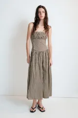 Vestido midi de popelín con estampado de rayas verticales. Presenta escote recto con detalle de pliegues, tirantes finos y falda con corte evasé. Incluye cierre lateral con cremallera oculta.