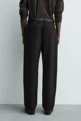 Pantalón straight fit color negro confeccionado en tejido con lana, con detalle de pliegues en el delantero, bolsillos frontales y traseros, y cierre frontal con cremallera y botón.