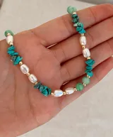 Collar de diseño artesanal que combina piedras naturales en tonos verdes y turquesas con perlas irregulares y pequeñas cuentas doradas.