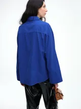 Camisa oversize de lyocell color tostado, con cuello clásico, cierre frontal de botones y mangas largas con puños anchos. Presenta un diseño de corte relajado con caída fluida.