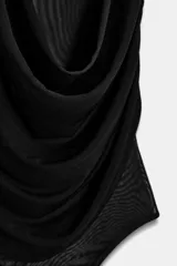 Body negro de tul con cuello alto y sisas amplias. Diseño drapeado en el frente y cierre inferior con broches a presión.