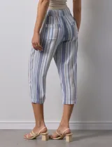 Pantalón capri de lino estampado con rayas verticales en tonos rosa, gris y amarillo. Tiene pretina ancha elastizada, bolsillos inclinados en la parte delantera y cordón ajustable en la cintura.