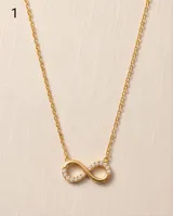 Collar de acero con baño de oro, con dije en forma de símbolo de infinito parcialmente incrustado con circonias.