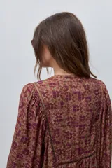 Vestido largo de silueta amplia y caída fluida, con estampado y recortes fruncidos que aportan movimiento. Presenta escote con abertura, cierre frontal con botones y mangas largas de volumen amplio con puños elastizados.