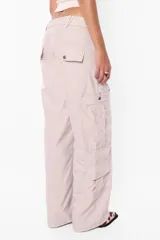 Pantalón cargo negro de corte recto y tiro bajo, con recortes y múltiples bolsillos laterales y traseros con tapa y botón a presión. Cierre frontal con cremallera de nylon y botón personalizado.