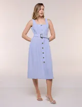 Vestido midi abotonado verde melange, con escote recto, tirantes anchos y falda de calce recto con vuelo sutil. Tiene abotonadura frontal completa con botones estilo carey, cinto textil con hebilla para ajustar la cintura y bolsillos laterales.