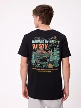 Remera de manga corta color negro con estampado gráfico en la espalda que representa un paisaje de montaña, bosque y carpa, con el logo de la marca Rusty y la frase Warmed by Nature.