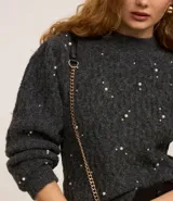 Buzo de tricot texturizado color gris con perlas blancas aplicadas. Tiene mangas largas abullonadas y cuello redondo.