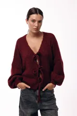 Saco tejido de punto color azul, con escote en V y cierre frontal mediante lazos. Presenta mangas largas amplias con puños ajustados y un calce relajado.