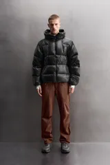 Campera puffer negra con capucha ajustable, cierre frontal con cremallera, bolsillos laterales con cremallera oculta y relleno de plumón y pluma.