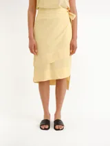 Pollera midi color amarillo claro, tipo envolvente (wrap), con diseño asimétrico en capas y lazo lateral para anudar.