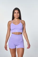 Conjunto deportivo de dos piezas en color lila, compuesto por un top de breteles finos con diseño acanalado y logo estampado, y un short de tiro alto de calce ajustado.