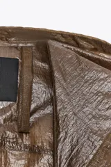 Chubasquero tipo capa oversize con capucha ajustable, manga larga y cierre frontal con botones a presión. Presenta un diseño con bolsillos delanteros y bajo asimétrico con aberturas laterales.