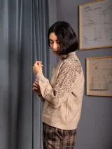 Buzo de cuello alto color gris, de manga larga, con detalle de bordado floral con lentejuelas en el hombro y parte superior de la manga.