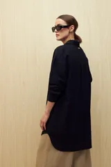 Vestido camisero negro de silueta amplia, con cuello camisero, botonadura frontal completa y mangas largas.