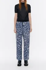 Pantalón fluido de viscosa con estampado abstracto en tonos azules y grises. Modelo de corte recto, largo tobillero, cierre frontal con cremallera de plástico, bolsillos falsos con tapetas laterales y cintura con elástico interior.