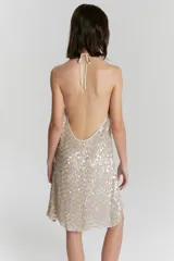 Vestido corto color beige con lentejuelas plateadas, de breteles finos y corte suelto.