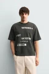 Camiseta de algodón con corte relajado, cuello redondo y manga corta. Presenta estampados gráficos a contraste en el frente con inscripciones tipo señalética.