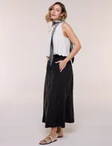 Falda midi evasé de algodón color negro, con tiro alto, pretina con elástico posterior, abotonadura frontal con botones carey y bolsillos laterales.