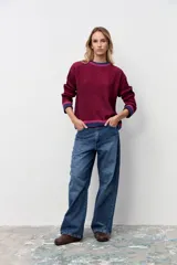 Pullover oversize de punto acanalado en color bordó, con cuello redondo y detalles de franjas en contraste en color azul y fucsia en el cuello, puños y ruedo.