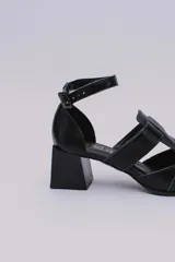 Sandalias plateadas con punta cerrada, tiras entrecruzadas y pulsera al tobillo con hebilla. Taco cuadrado negro.